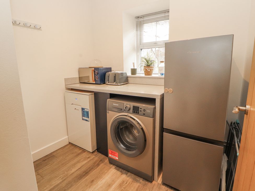 A laundry room with washing machine and refrigerator at Blue heron lodge in Kirkby Stephen
