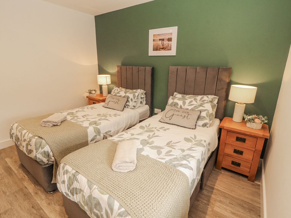 A bedroom with two beds and bedside tables at Blue Heron Lodge in Kirkby Stephen