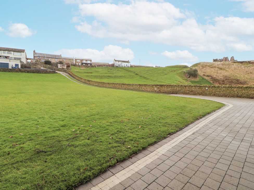 A grassy outdoor area with a paved path and houses at Blue heron lodge, Kirkby Stephen
