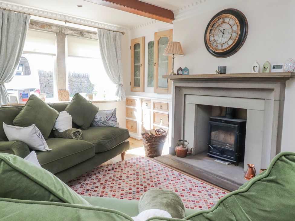 A living room with a green sofa and fireplace at Vasey Croft in Stanbury near Haworth