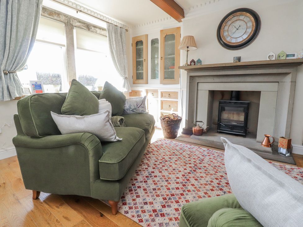 A living room with a green sofa and fireplace at Vasey Croft in Stanbury near Haworth