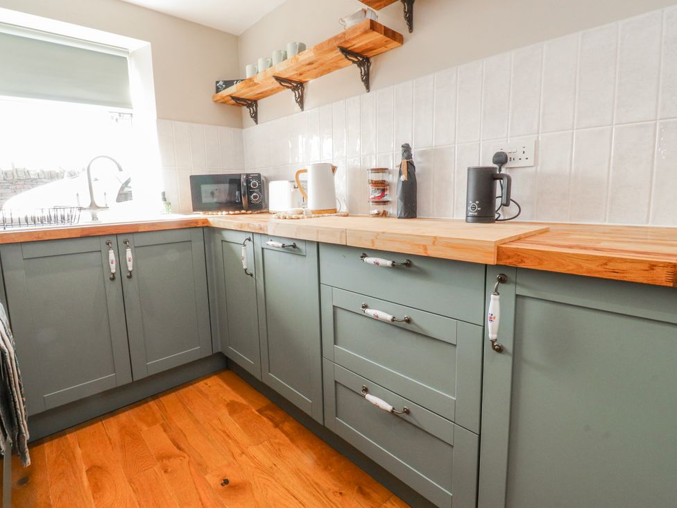 A kitchen with a sink, microwave, kettle and cabinets at Vasey Croft in Stanbury near Haworth