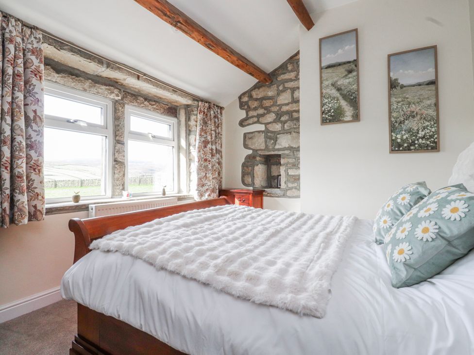 A bedroom with a bed and windows at Vasey Croft in Stanbury near Haworth