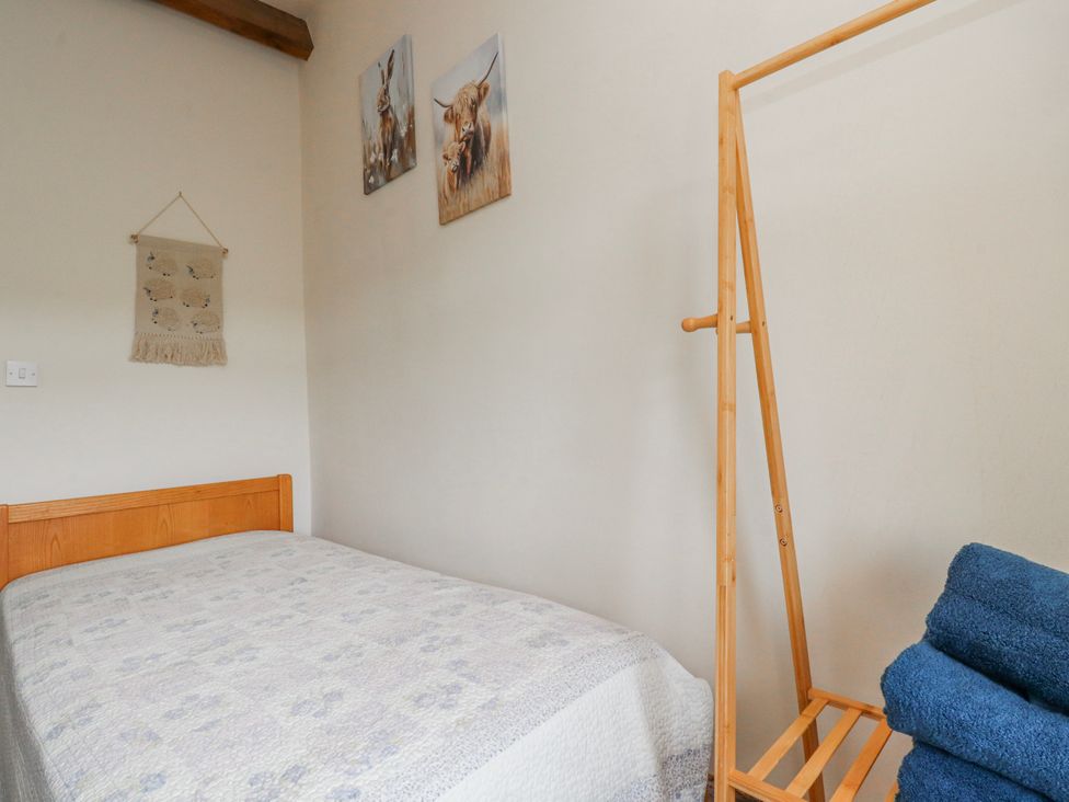 A bedroom with a bed and a towel rack at Vasey Croft in Stanbury near Haworth