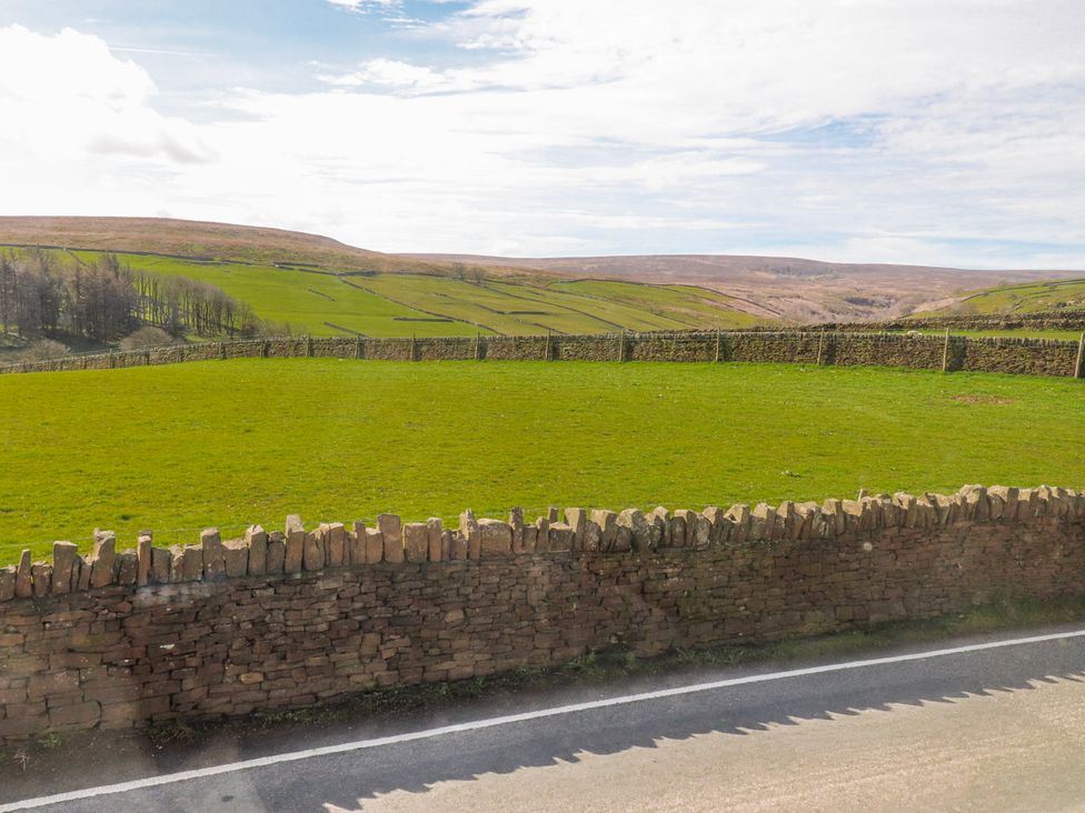 A green field with a stone wall in the countryside at Vasey Croft Stanbury near Haworth