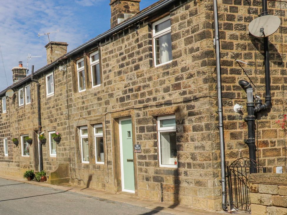 An exterior view of a stone cottage with a door and windows at Vasey Croft in Stanbury near Haworth