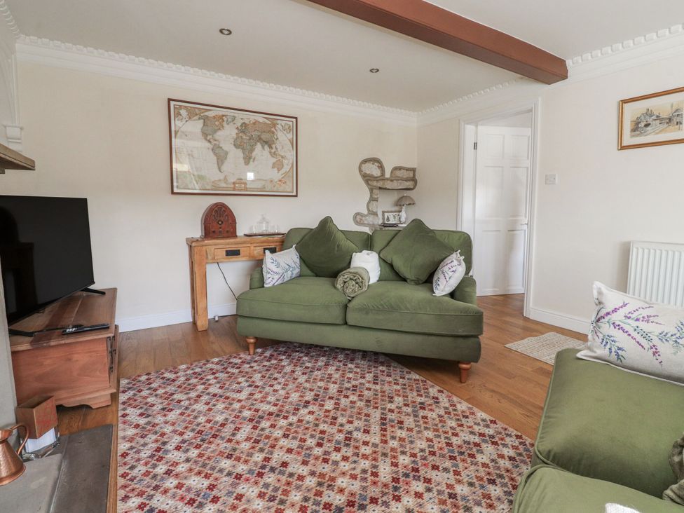 A living room with a green sofa and a television at Vasey Croft in Stanbury near Haworth