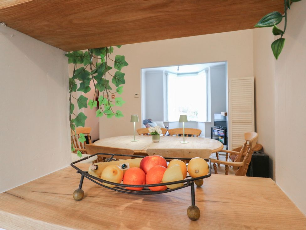 A fruit bowl on a table with green lamps in a dining room at Meregate Cottage, Margate