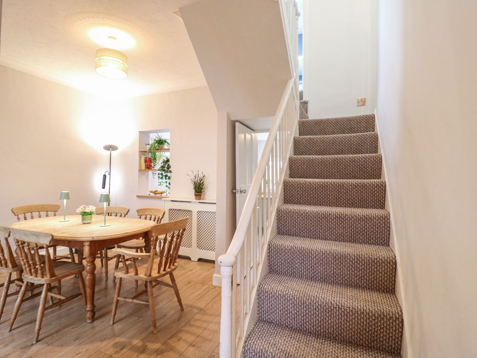 A dining room featuring a table with chairs and stairs at Meregate Cottage in Margate
