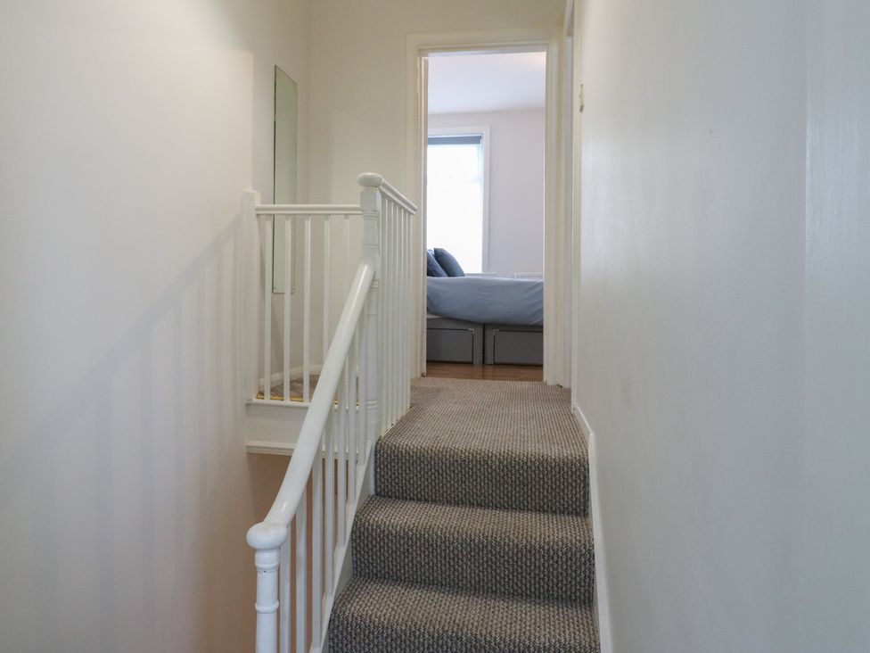 A hallway with a staircase and a door leading to a bedroom at Meregate Cottage in Margate