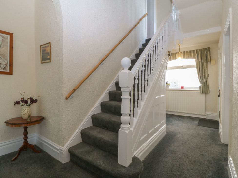 A hallway with a staircase and a small table with a vase at Gwynfa in Old Colwyn