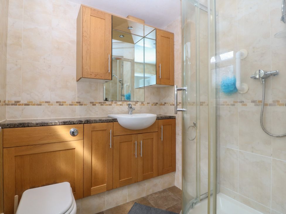 A bathroom featuring a sink, toilet, shower, and cabinets at Gwynfa in Old Colwyn