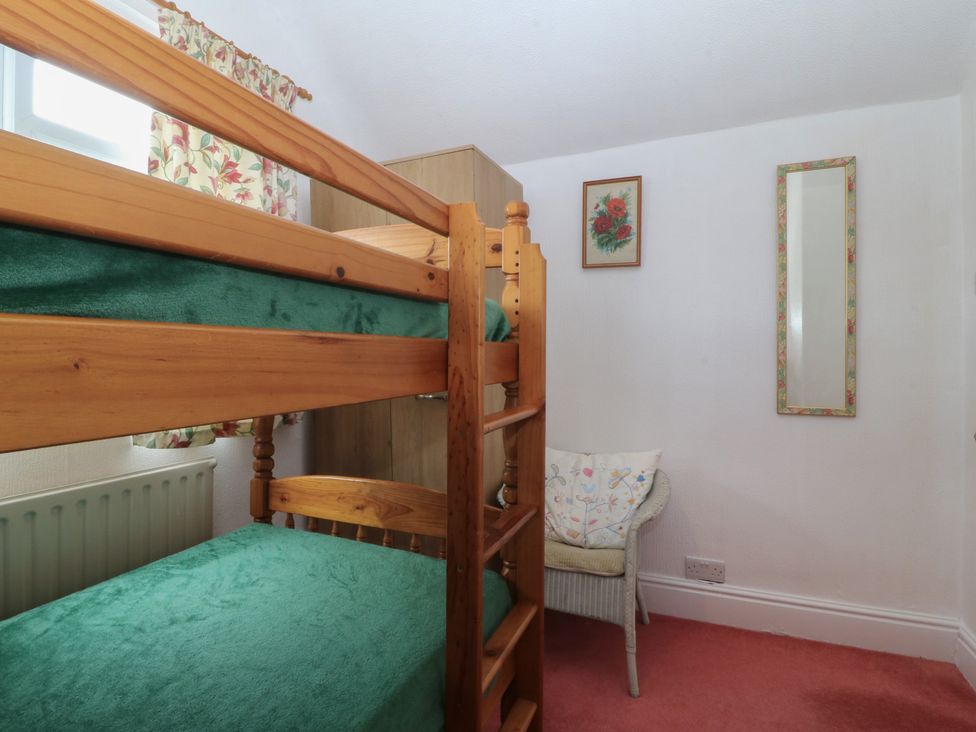 A bedroom with a bunk bed and chair at Gwynfa in Old Colwyn