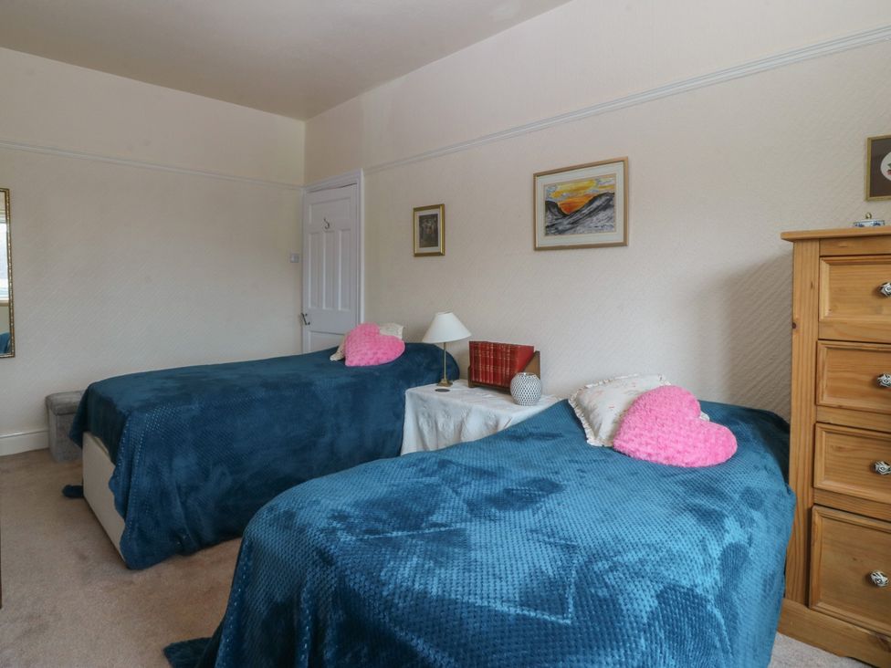 A bedroom with two beds and a nightstand at Gwynfa Old Colwyn
