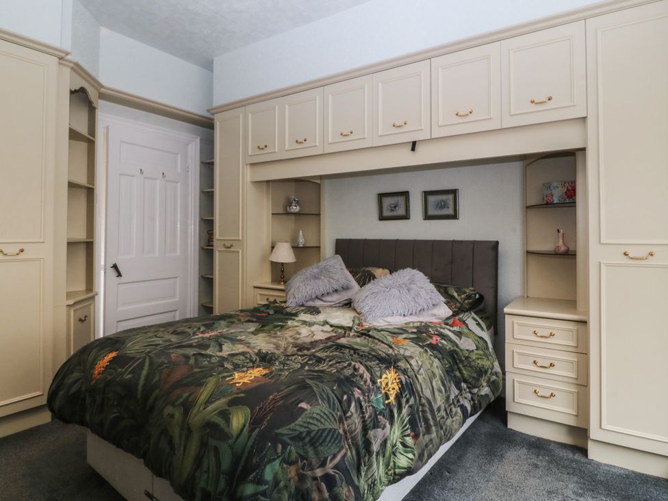 A bedroom with a bed and storage furniture at Gwynfa in Old Colwyn