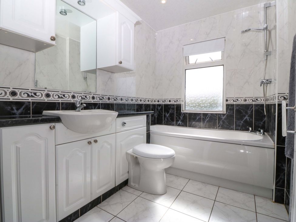A bathroom with a sink, toilet, and bathtub at Gwynfa, Old Colwyn