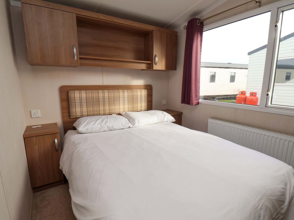 A bedroom with a double bed and a window at Caravan B14 Beechrise in Filey