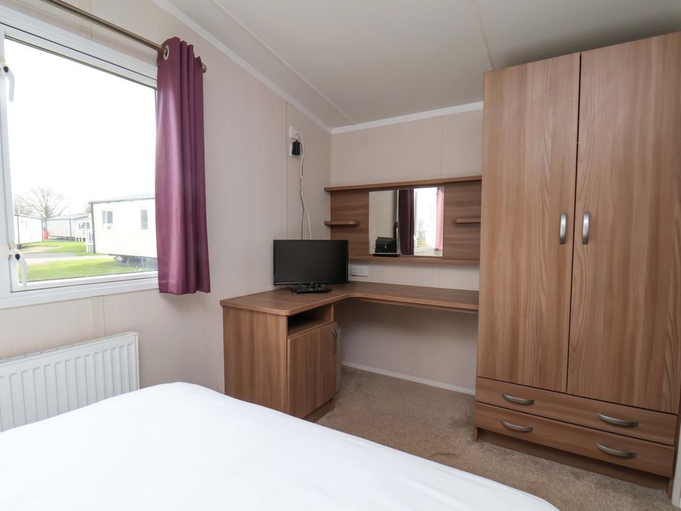 A bedroom with a desk and a wardrobe at Caravan B14 Beechrise in Filey