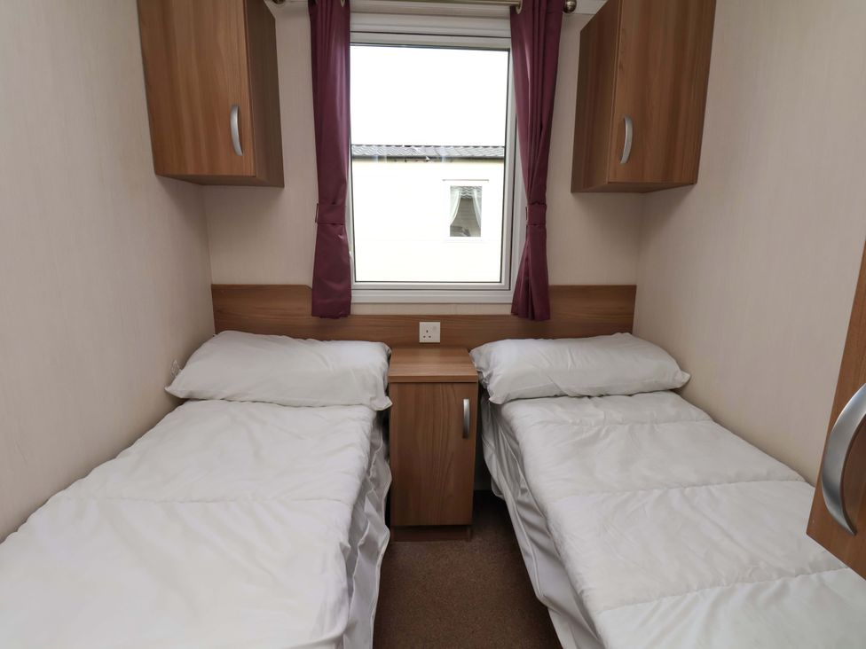 A bedroom with two single beds and a window at Caravan B14 Beechrise in Filey