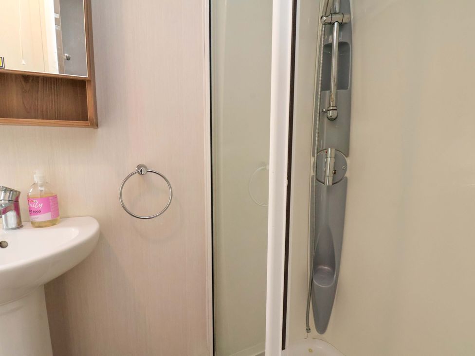A bathroom with a washbasin, mirror, towel ring, and shower at Caravan B14 Beechrise, Filey
