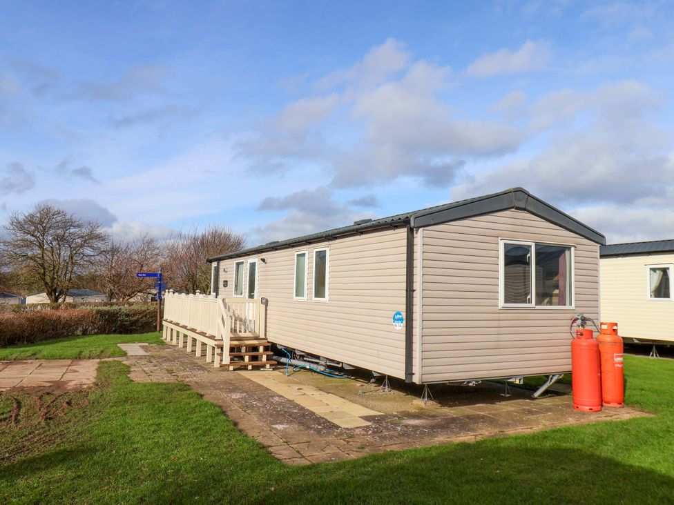 A mobile home with a deck and gas bottles at Caravan B14 Beechrise in Filey
