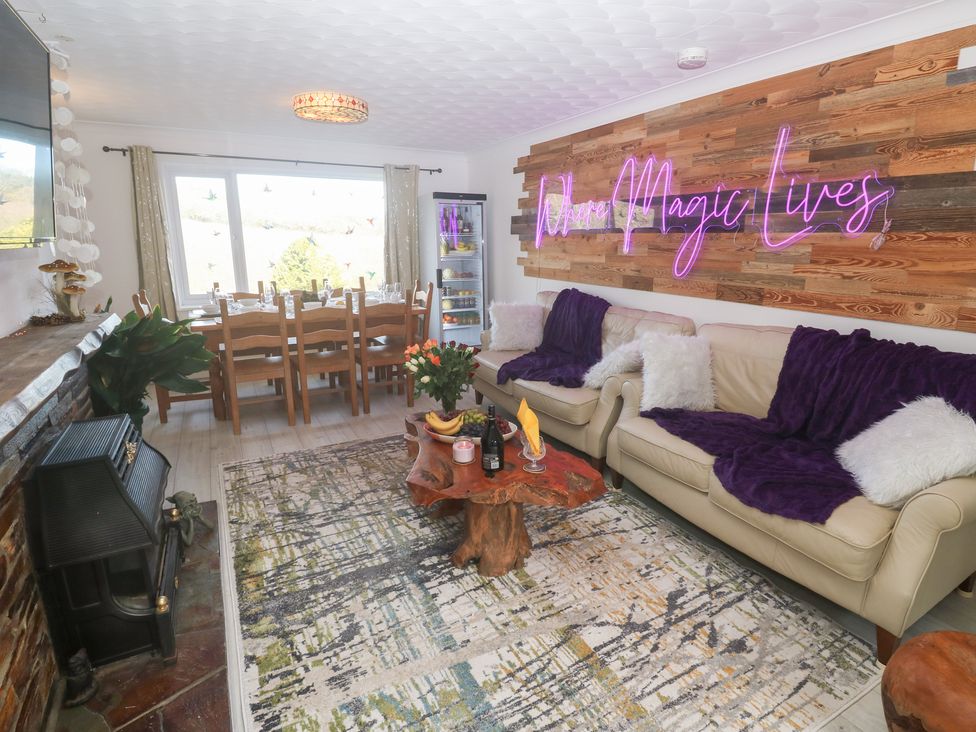 A living room with a sofa and dining area at Piskies Magic Home