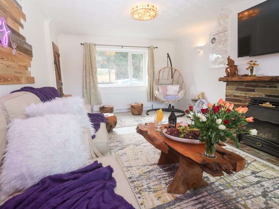 A living room with a sofa and table with flowers and grapes at Piskies Magic Home 