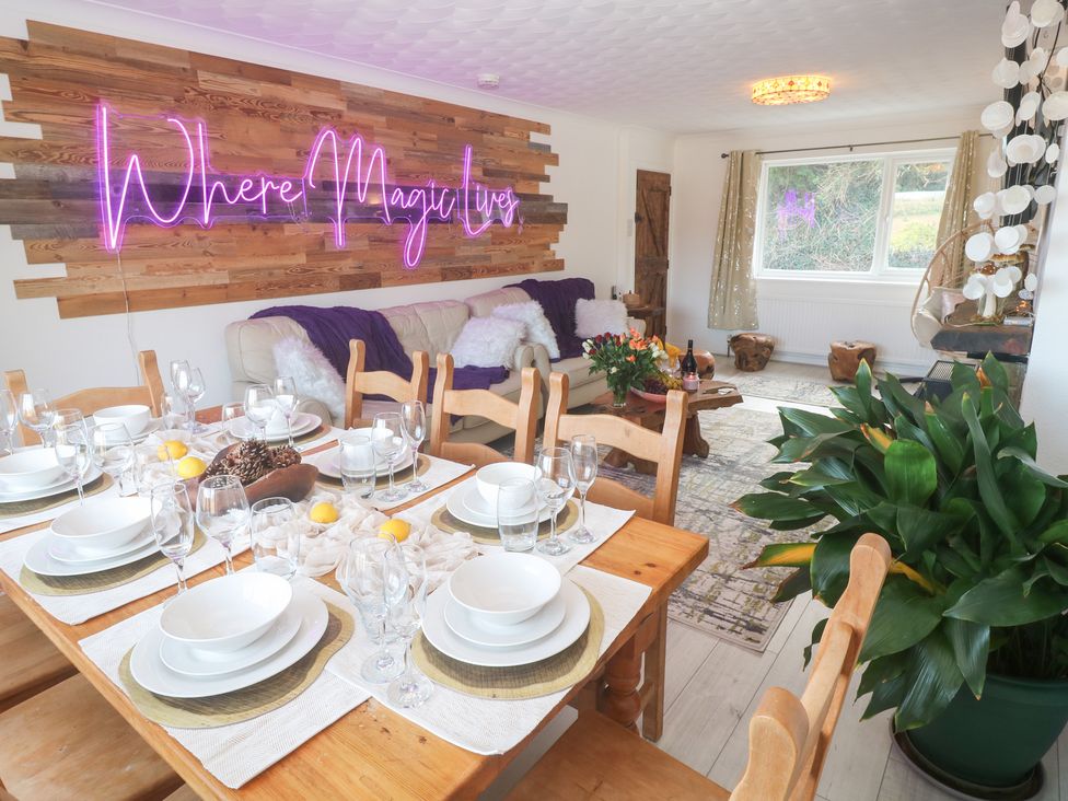 A dining table with tableware and a sofa at Piskies Magic Home