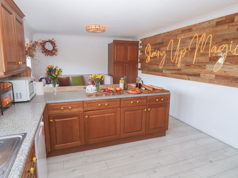 A kitchen with wooden cabinets and countertop at Piskies Magic Home 