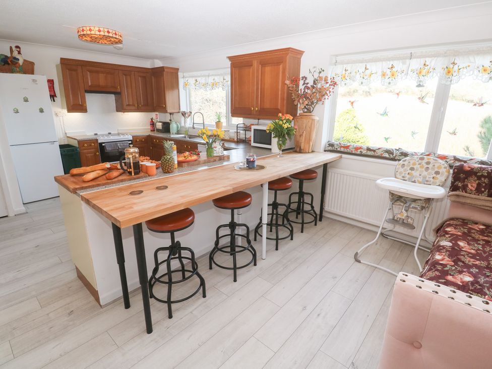 A kitchen with wooden cabinets and stools at Piskies Magic Home 