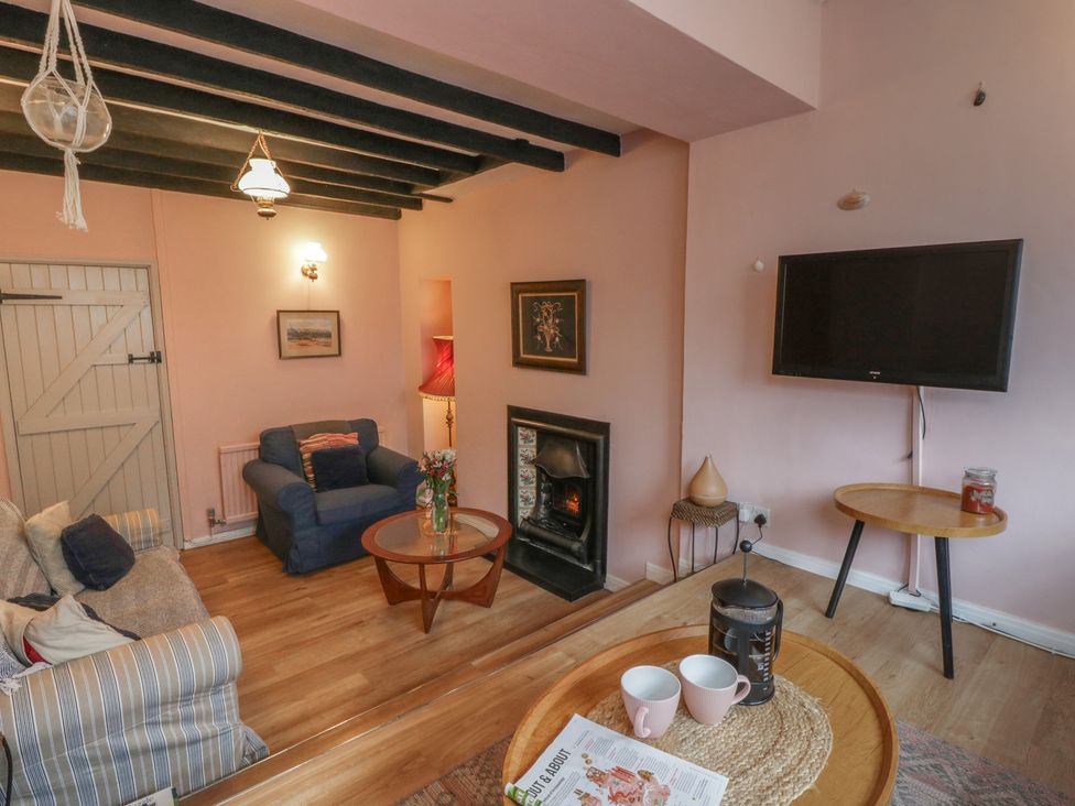 A living room with a sofa and television at 1 Alpha Cottages in Tenby