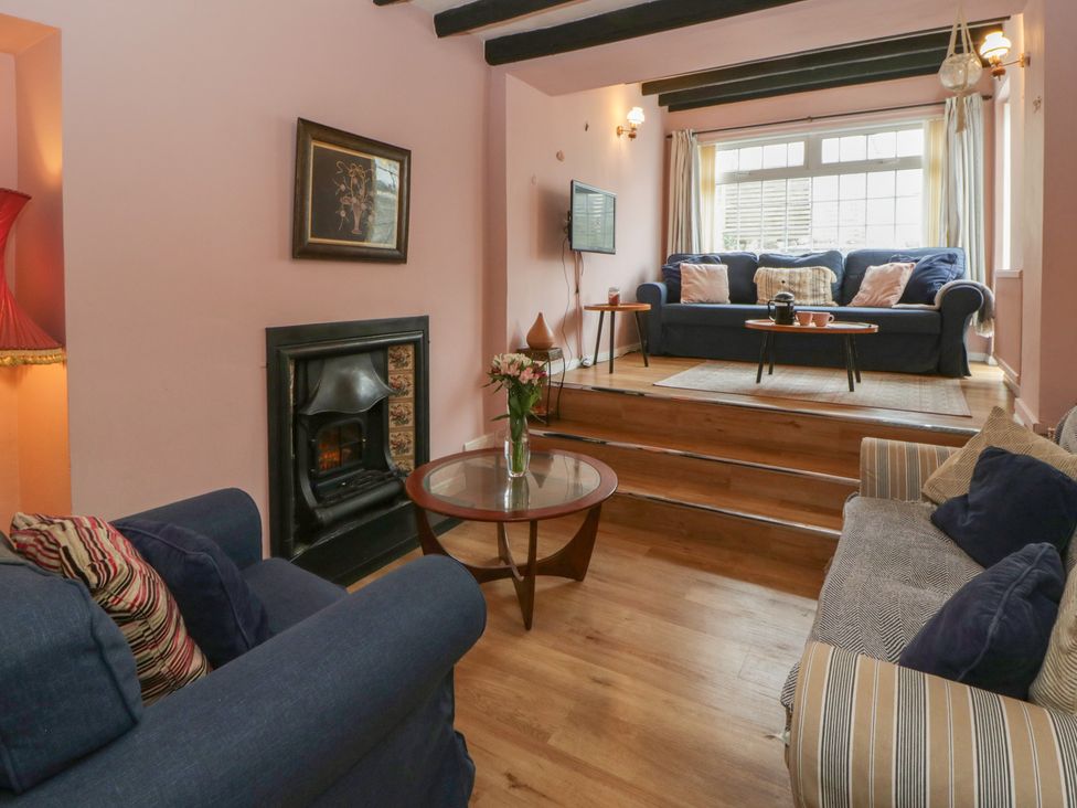 A living room with a fireplace and seating at 1 Alpha Cottages in Tenby