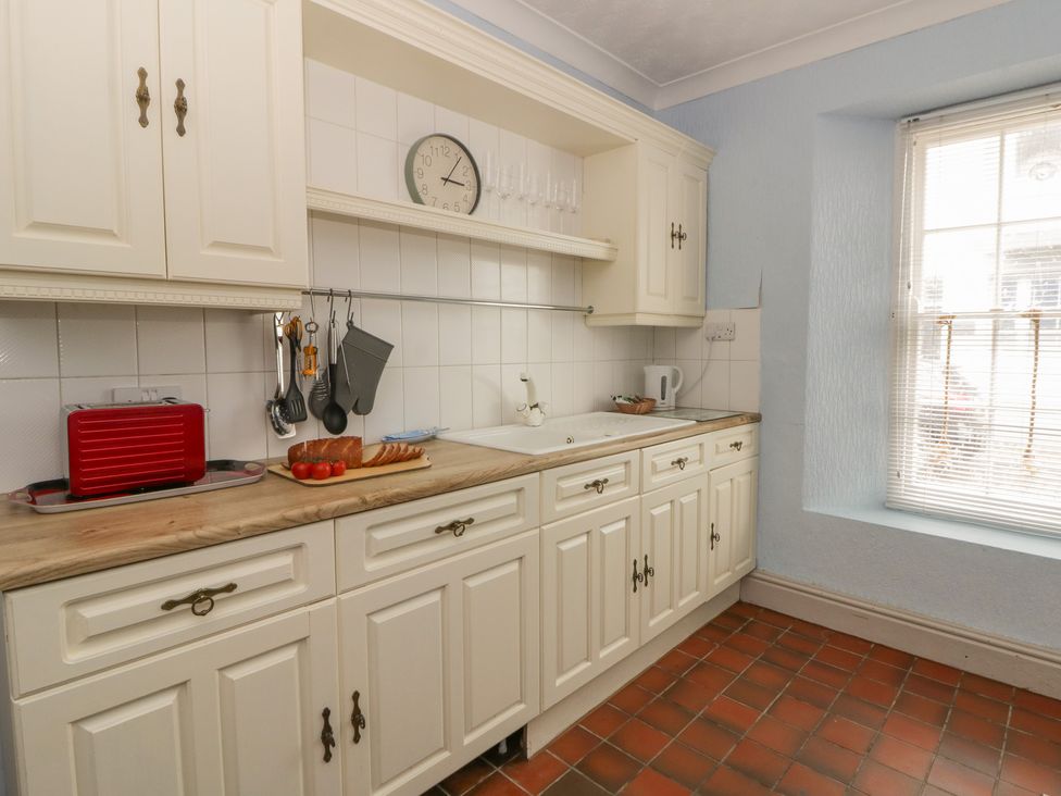 A kitchen with cabinets and a sink at 1 Alpha Cottages in Tenby