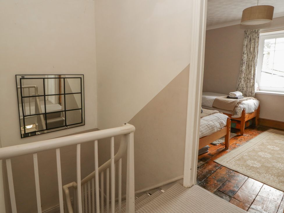 A bedroom with two beds and a window at 1 Alpha Cottages in Tenby