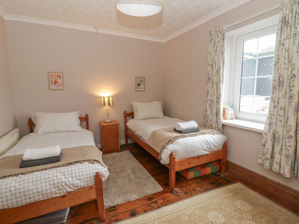 A bedroom with two beds and a window at 1 Alpha Cottages in Tenby