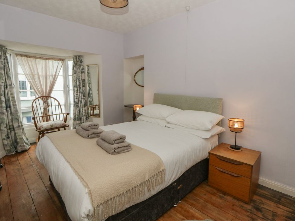 A bedroom with a bed and chair at 1 Alpha Cottages in Tenby