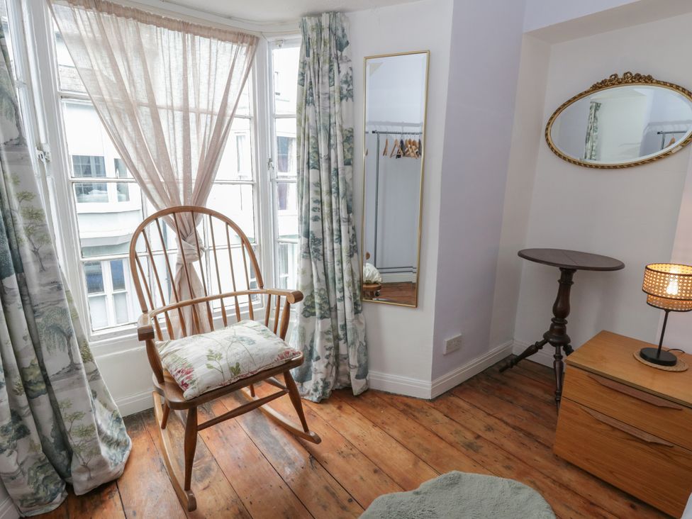 A bedroom with a rocking chair and mirror at 1 Alpha Cottages in Tenby