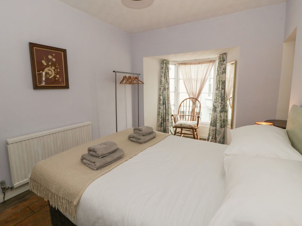 A bedroom with a bed and chair at 1 Alpha Cottages in Tenby
