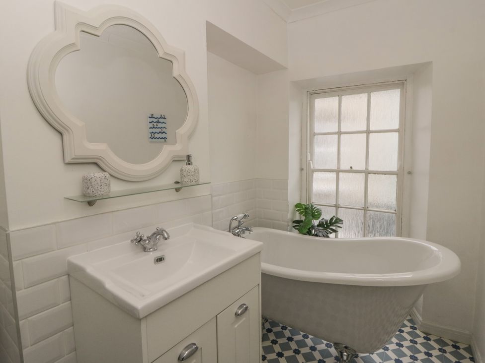A bathroom featuring a bathtub, sink, and mirror at 1 Alpha Cottages Tenby