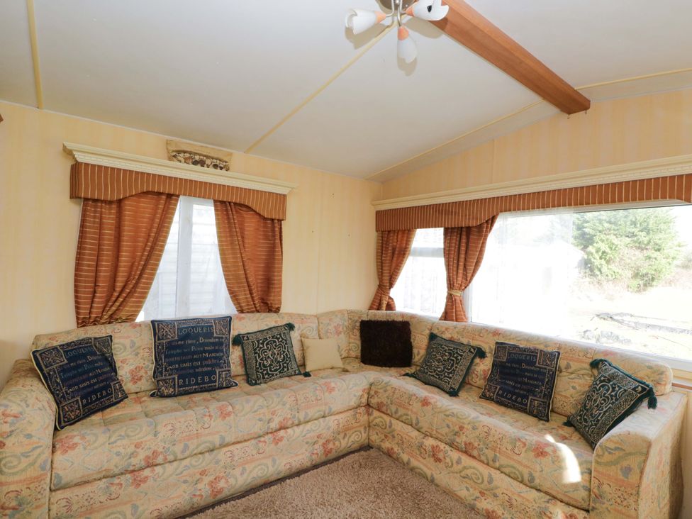 A living room with a sofa and cushions at Bengrove Wood Lodge in Shepton Mallet