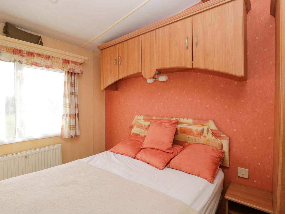 A bedroom with a bed and window at Bengrove Wood Lodge Shepton Mallet