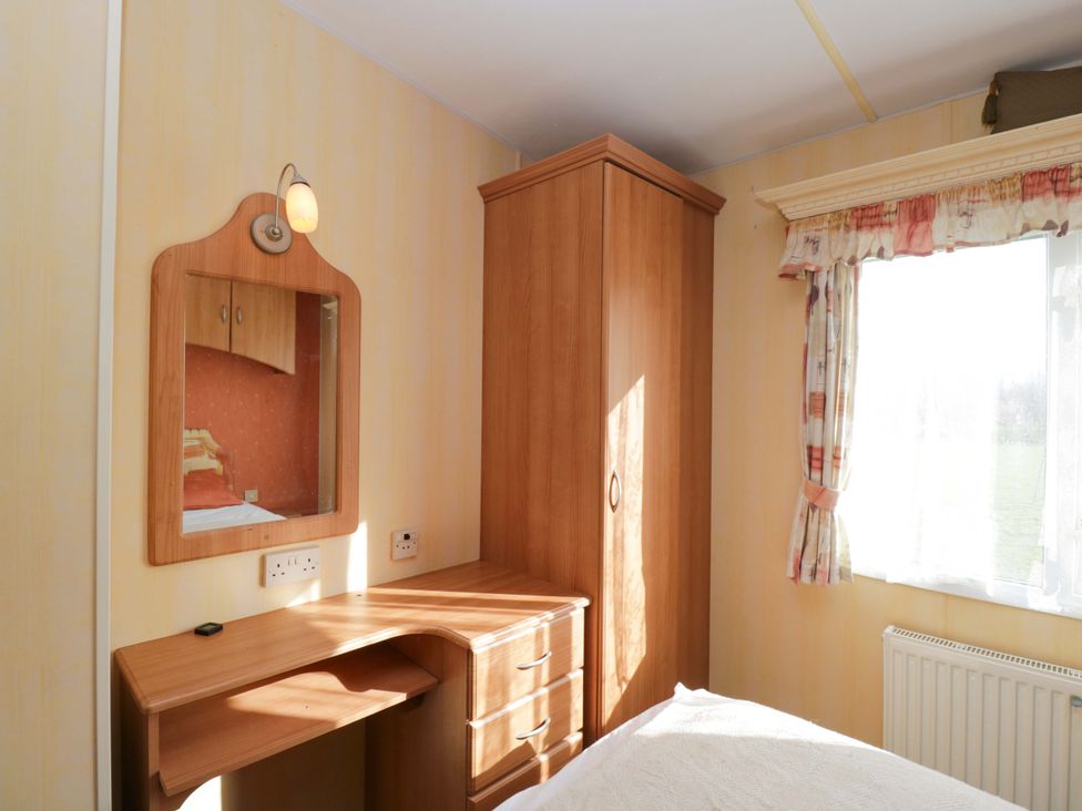 A bedroom with a mirror and a wardrobe at Bengrove Wood Lodge in Shepton Mallet
