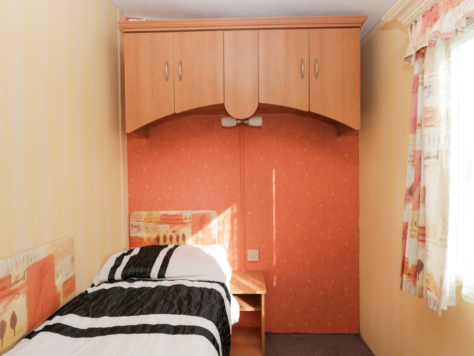 A bedroom with a single bed and wall cabinets at Bengrove Wood Lodge Shepton Mallet