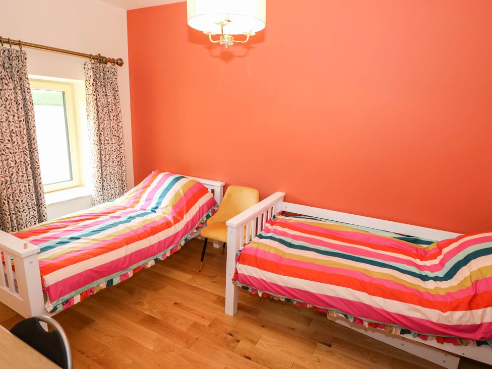 A bedroom with two beds and a chair at The Cottage in Leenane, County Galway