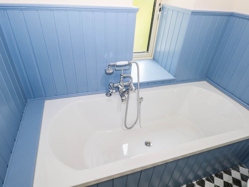 A bathtub with a faucet and a window at The Cottage in Leenane, County Galway