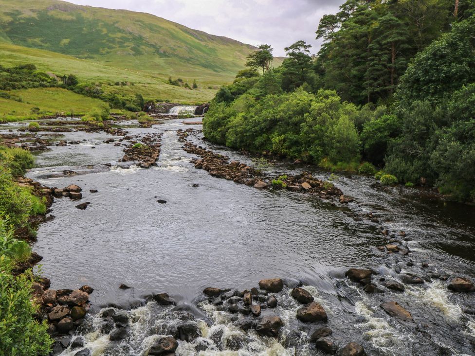 A river with rocks and trees at The Cottage in Leenane, County Galway