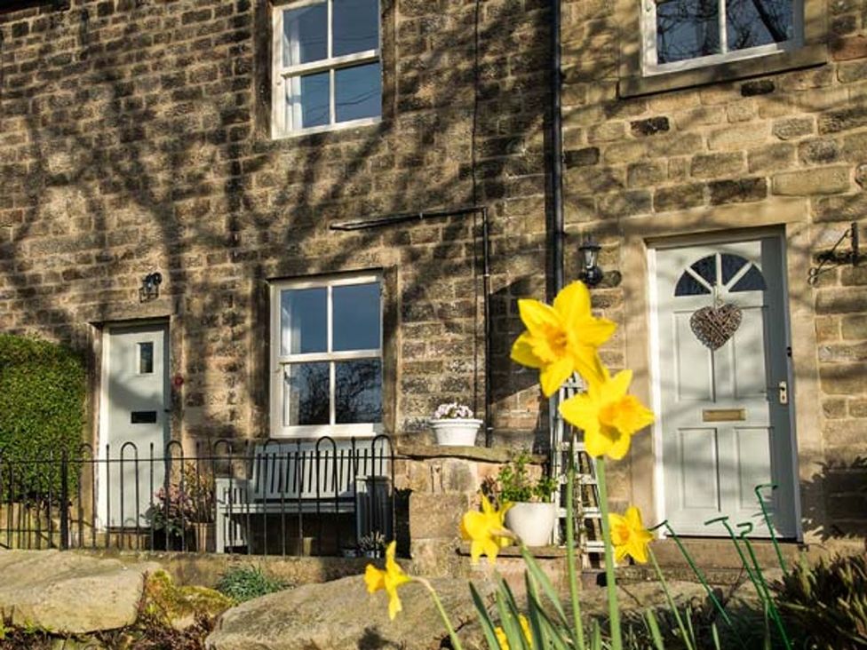 An outdoor view of a stone house with flowers at Beacon Cottage in Ilkley