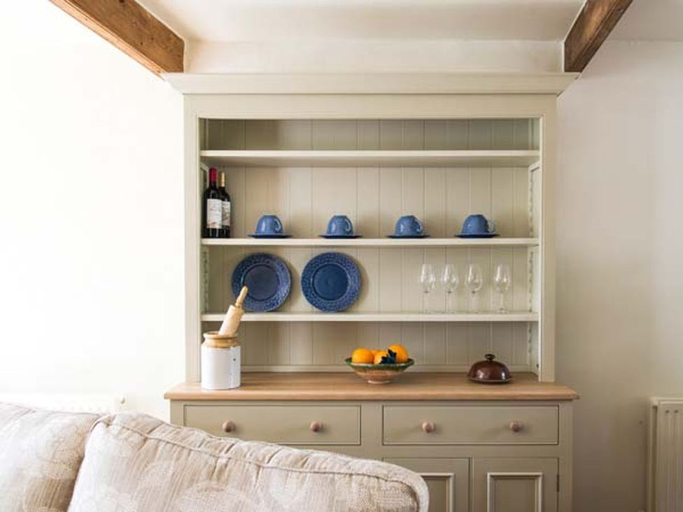 A storage cabinet with plates and cups at Beacon Cottage in Ilkley