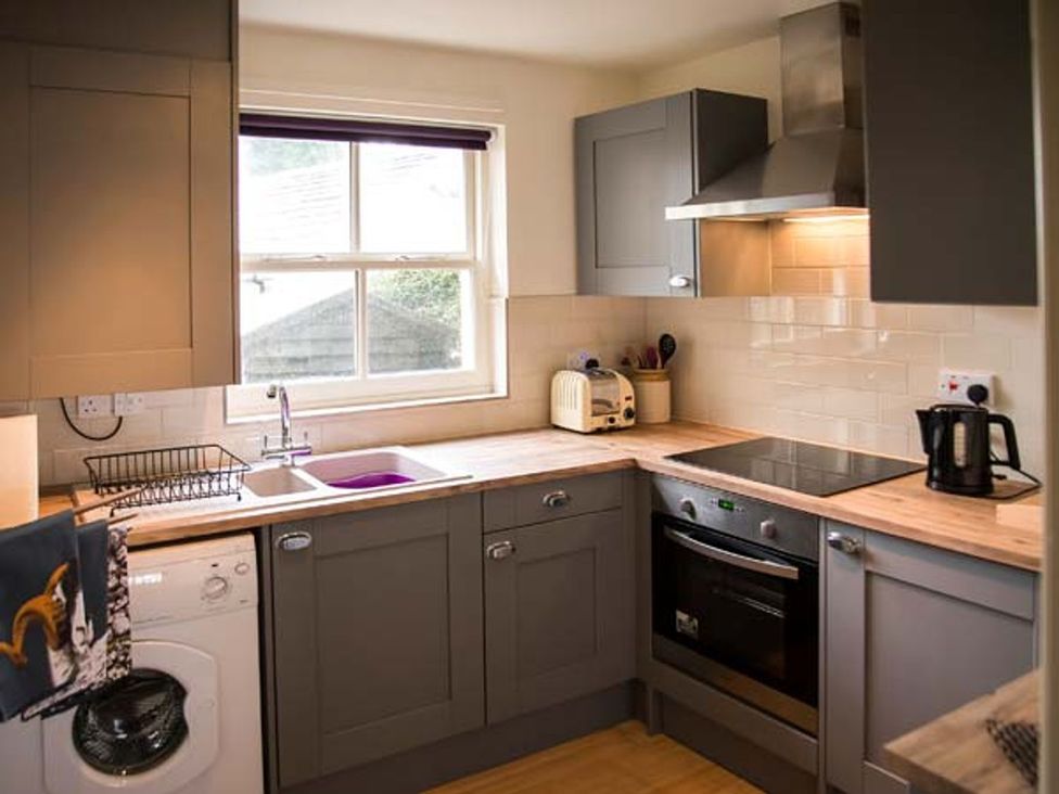 A kitchen with a sink, washing machine, and appliances at Beacon Cottage in Ilkley