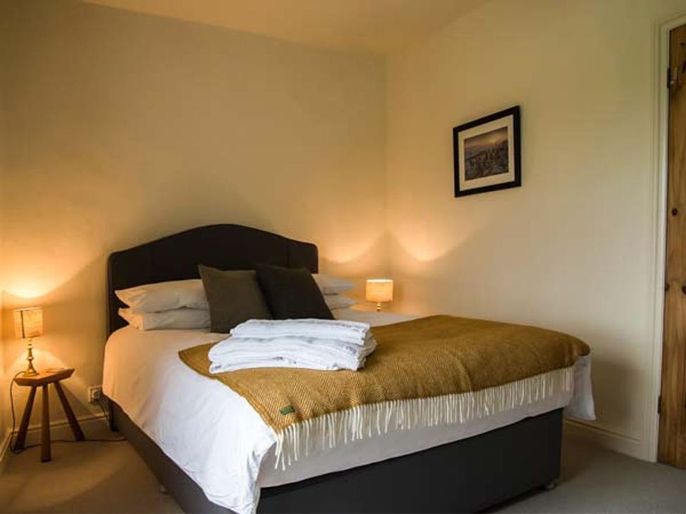 A bedroom with a bed and lamps at Beacon Cottage in Ilkley